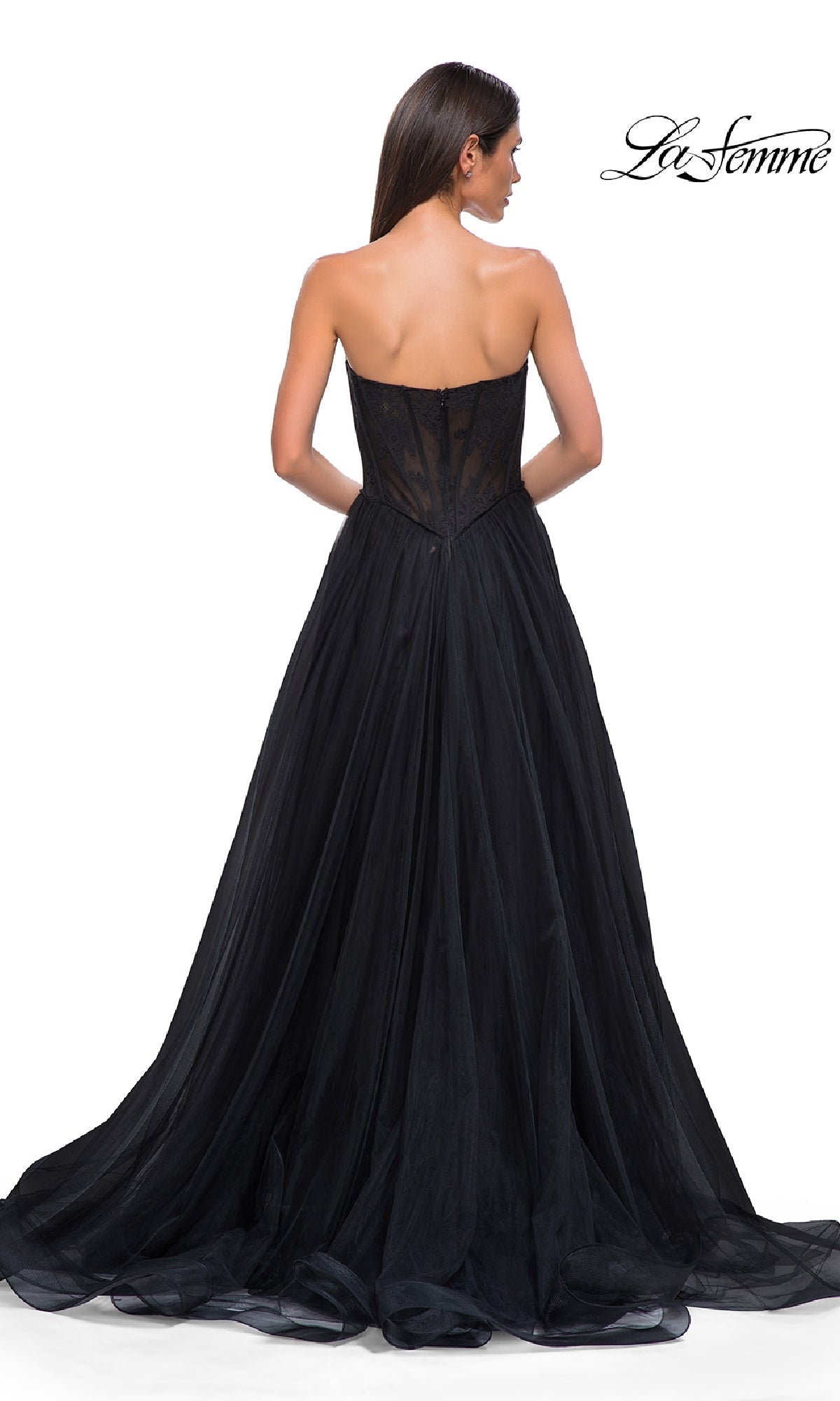 A woman is seen from the back wearing the Strapless Long Prom Ball Gown: La Femme 32579, featuring a floral corset-style bodice and a flowing black skirt. The La Femme logo appears in the top right corner.